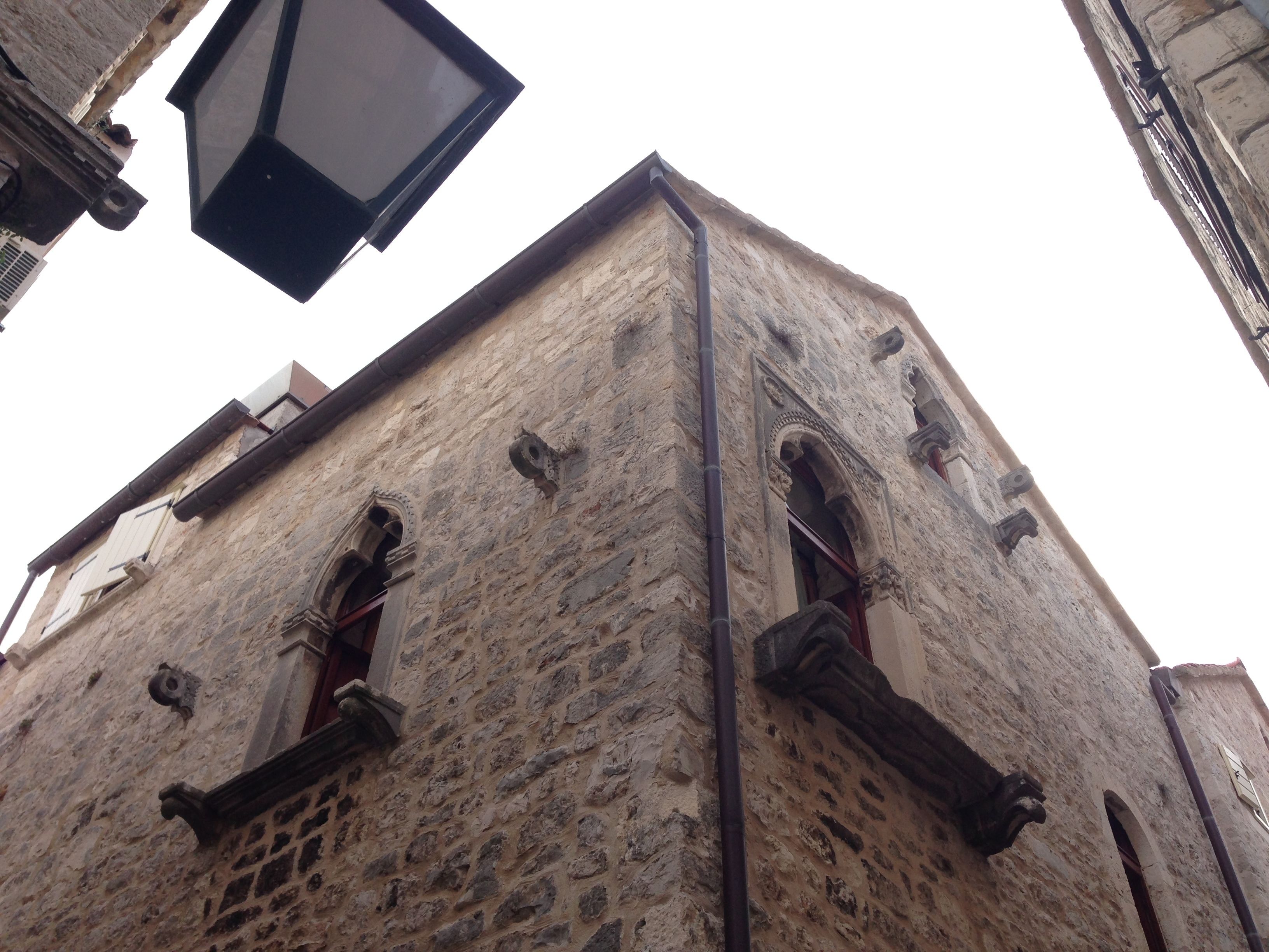A stone building with arched windows and a visible street lamp.
