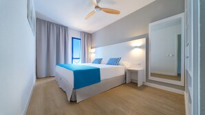 A modern hotel room with a bed, bedside table, and a ceiling fan.