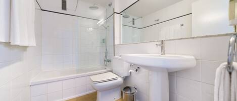 A modern bathroom with a bathtub, toilet, and shower area.
