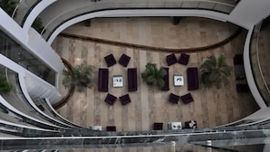 Un interior moderno con paredes curvas, una zona de estar central con mesas y sillas, y un suelo reflectante.
