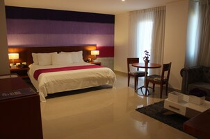 Una habitación de hotel con una cama grande, un escritorio, una silla y una mesita.