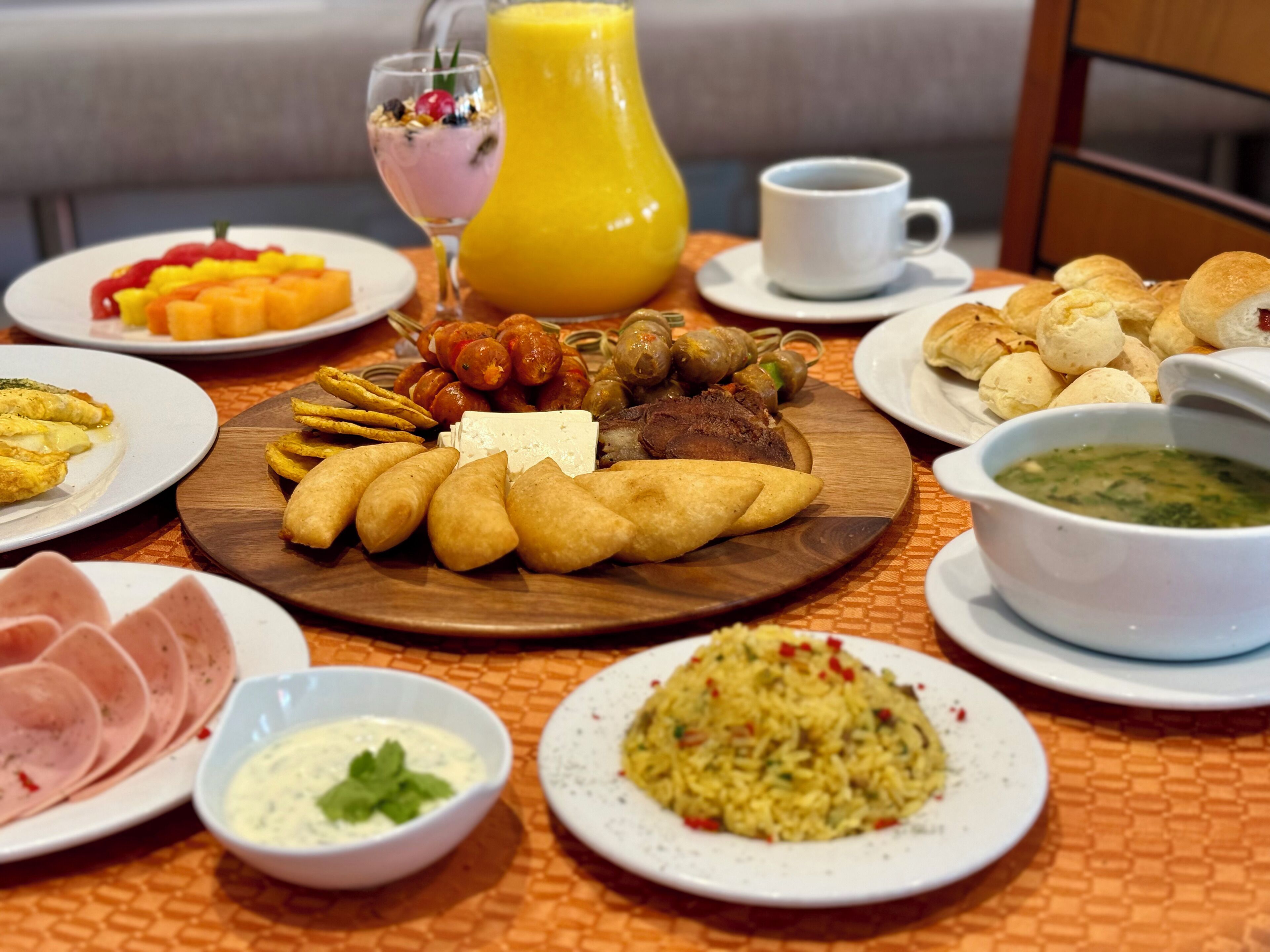 Un bufé de desayuno con diversos platos, incluyendo pasteles, carnes y una ensalada de frutas.