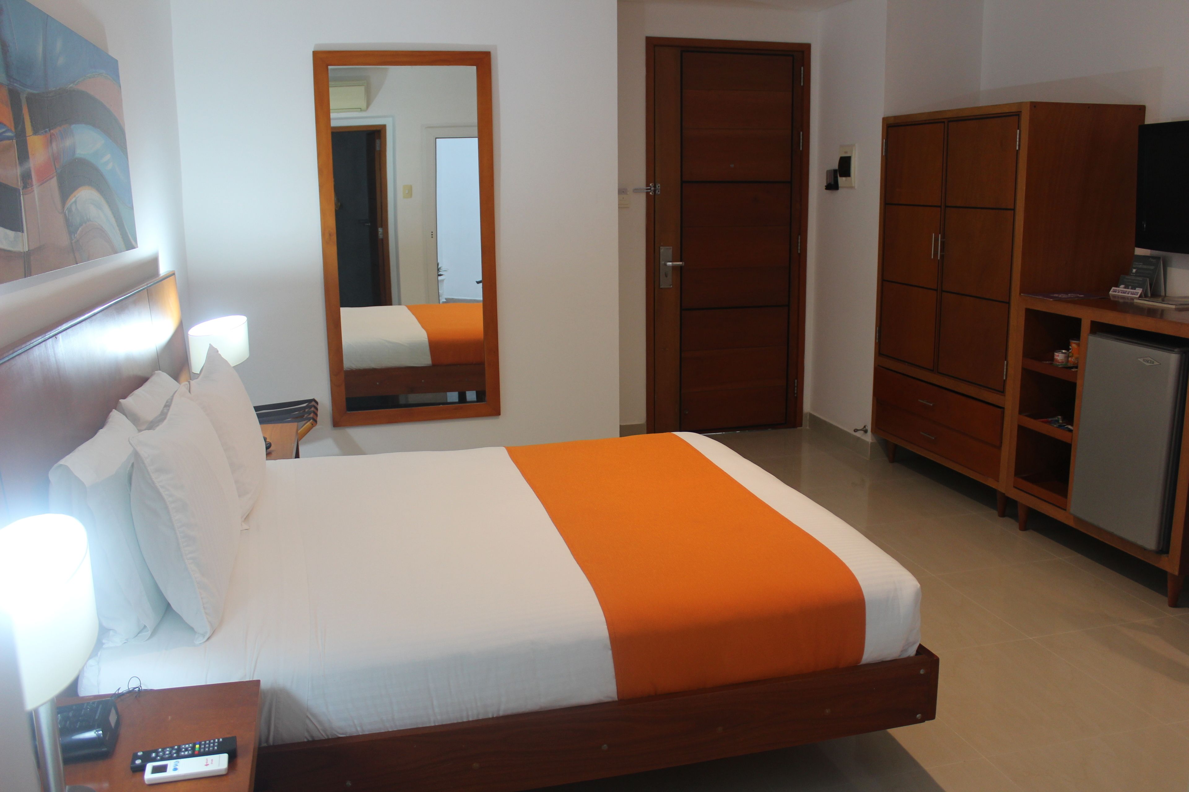 A hotel room with a bed, a nightstand, a mirror, a wardrobe, and a television.