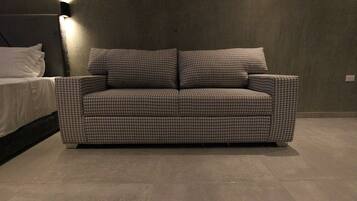 A houndstooth-patterned sofa in a modern room with a plain wall and a bed with white bedding.