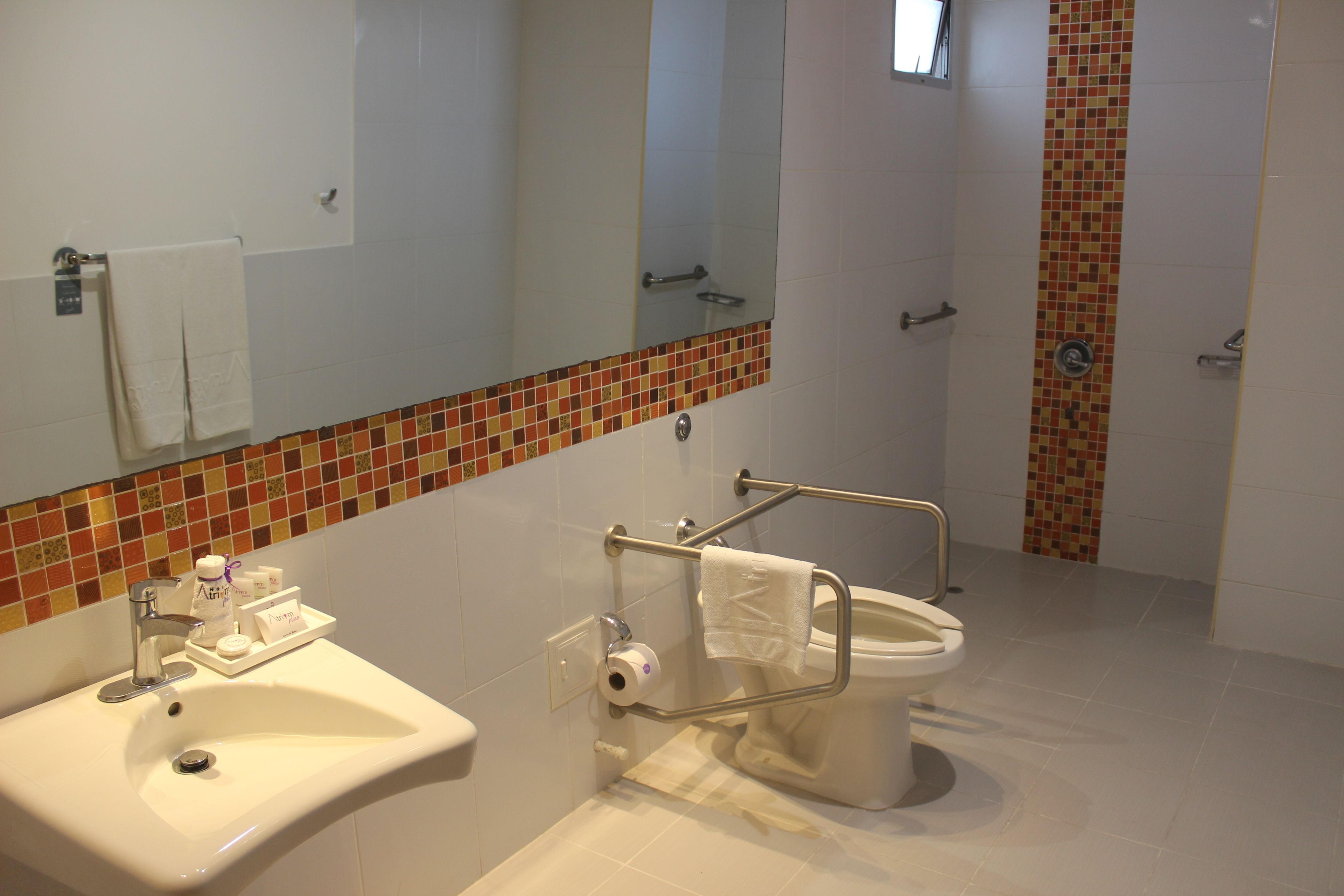 A bathroom with a sink, toilet, and mirror.