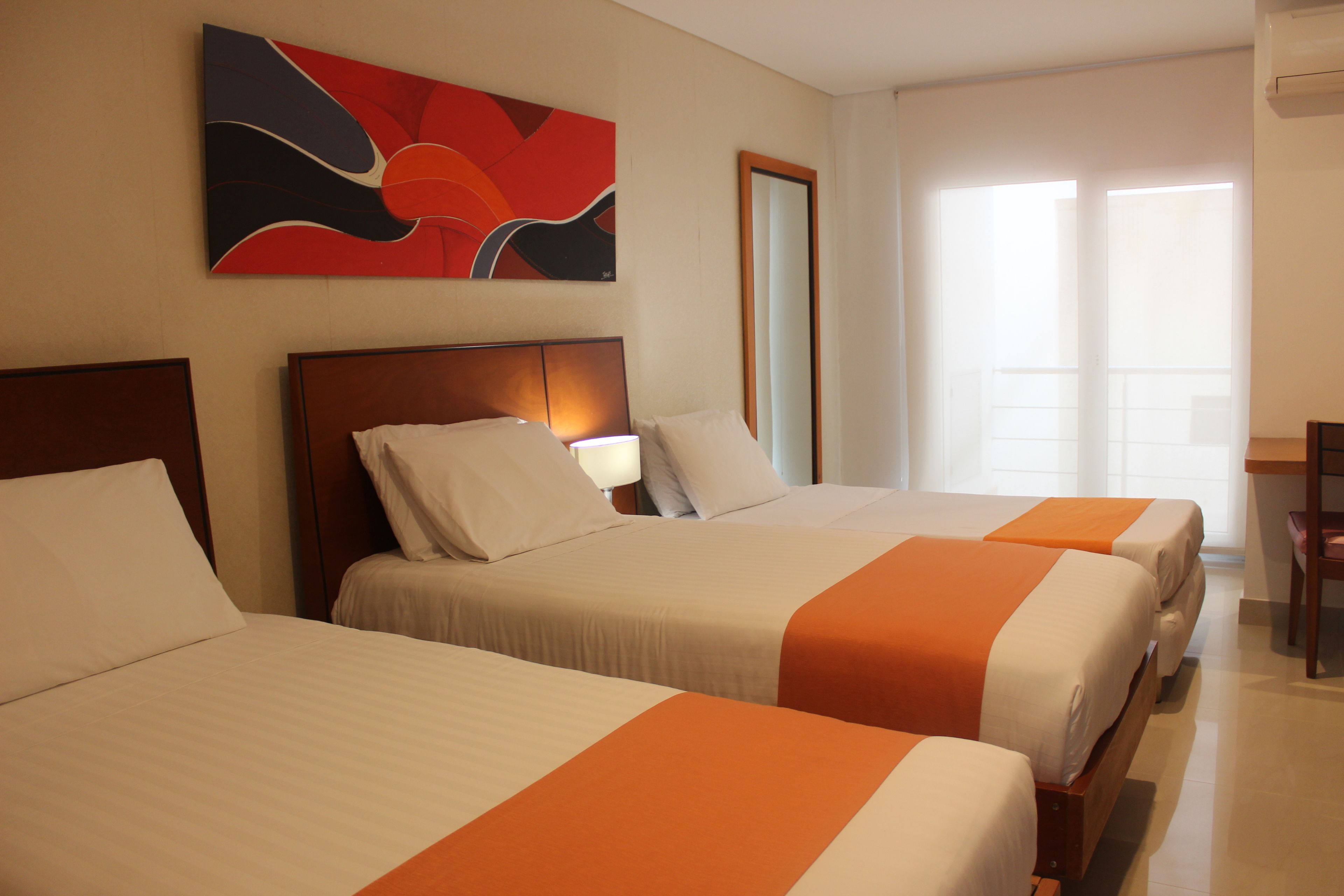 A hotel room with three beds, a large window with curtains, and a painting on the wall.