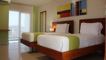 A hotel room with two beds, a large window, and a painting on the wall.