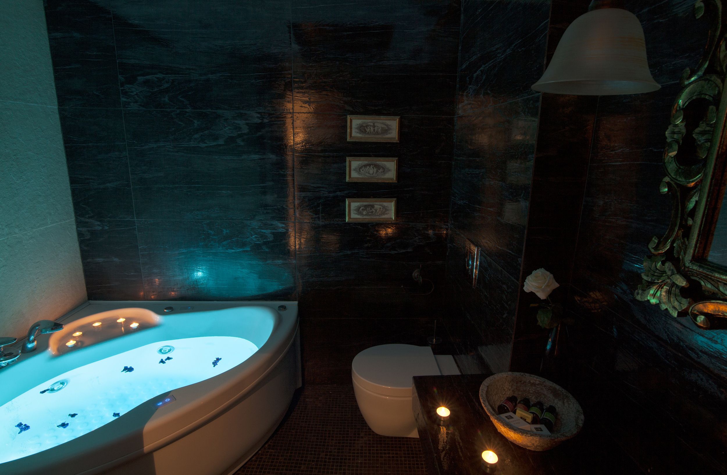 A modern bathroom with a freestanding bathtub, a toilet, a vanity with a mirror, and a wall-mounted light fixture.