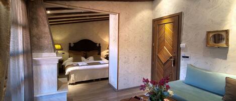 A hotel room with a bed, a sofa, a wooden coffee table, and a wall-mounted picture frame.