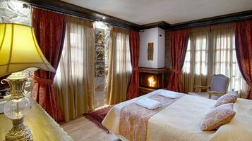 A hotel room with a large bed, a fireplace, a table with a lamp, and curtains.