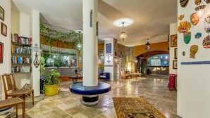 A spacious lobby with a central column, bookshelves, a patterned rug, and a decorative wall with masks. - Villa Asina (Datça)