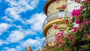 A stone building with a balcony, surrounded by pink flowers. - Villa Asina (Datça)