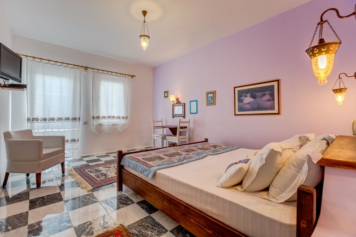 A bedroom with a bed, a chair, a desk, and a television.
