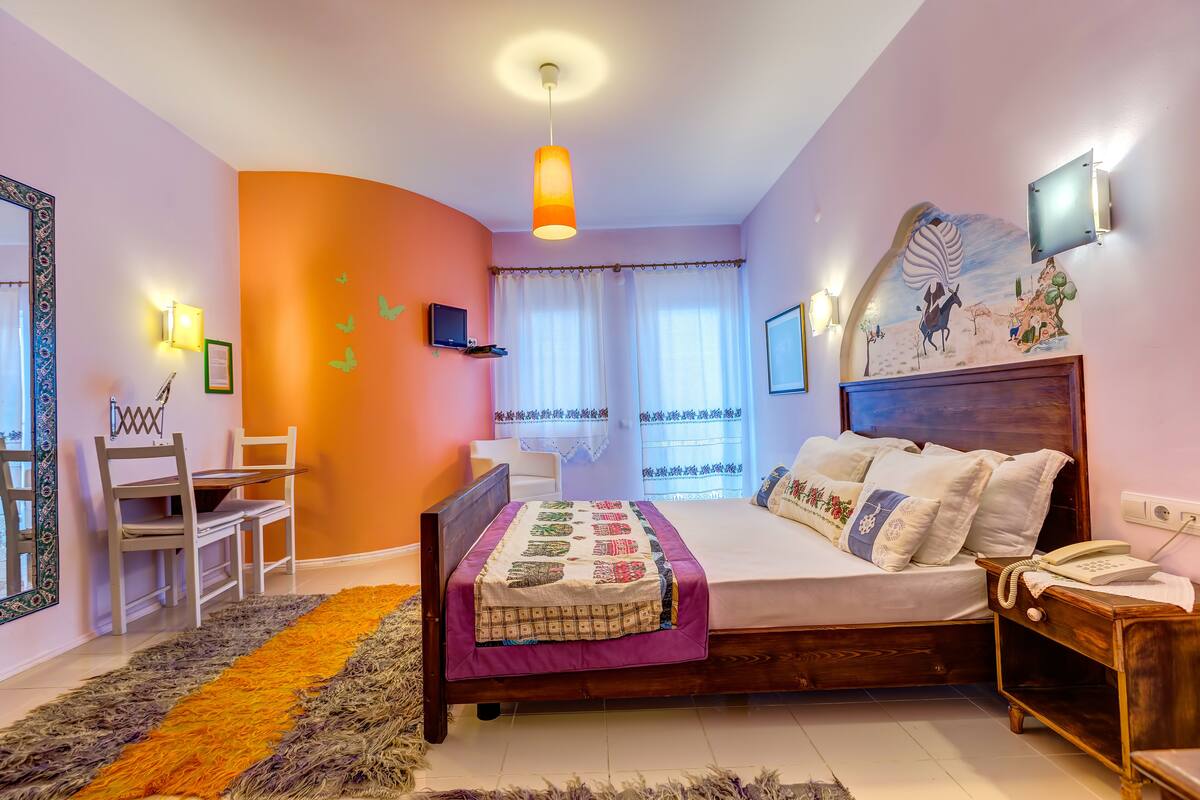 A bedroom with a bed, bedside table, lamp, and a wall-mounted TV.