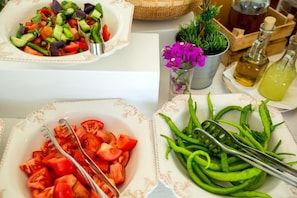 A table with a salad, sliced tomatoes, and green peppers.