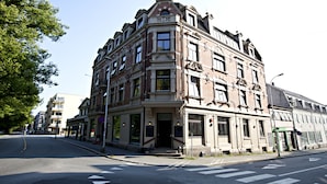 A historic building with a corner entrance, large windows, and a prominent clock tower.