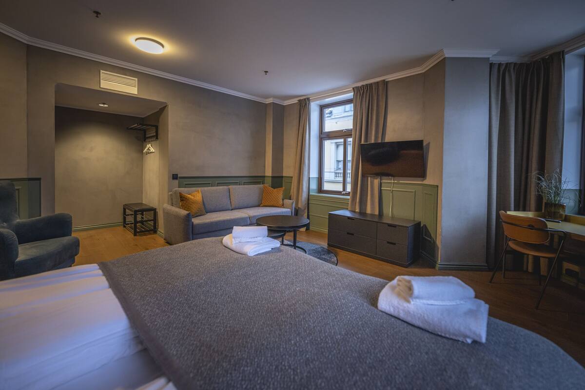 Una habitación de hotel con una cama grande, un sofá, un escritorio y un televisor.