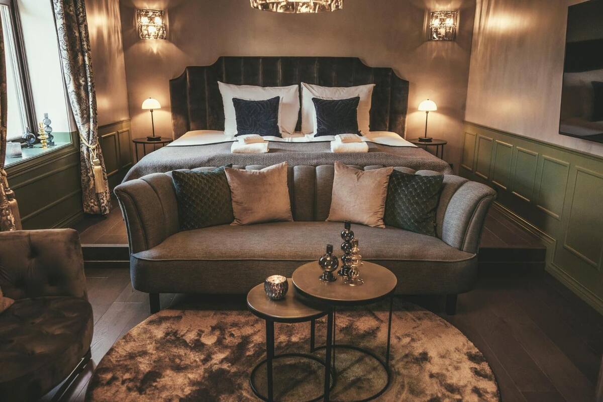 Un dormitorio lujoso con una cama grande, un sofá y una mesita con adornos.
