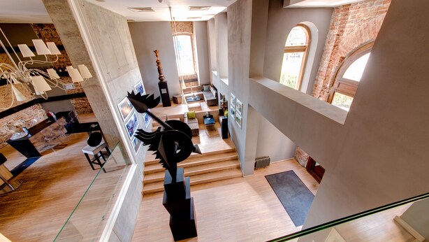 A spacious, multi-level interior with a modern design, featuring a staircase, seating areas, and a unique sculpture. - Sarroglia (Bucharest)