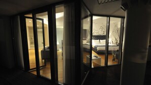 Un intérieur moderne avec une cloison en verre séparant l’espace de vie de la chambre à coucher.