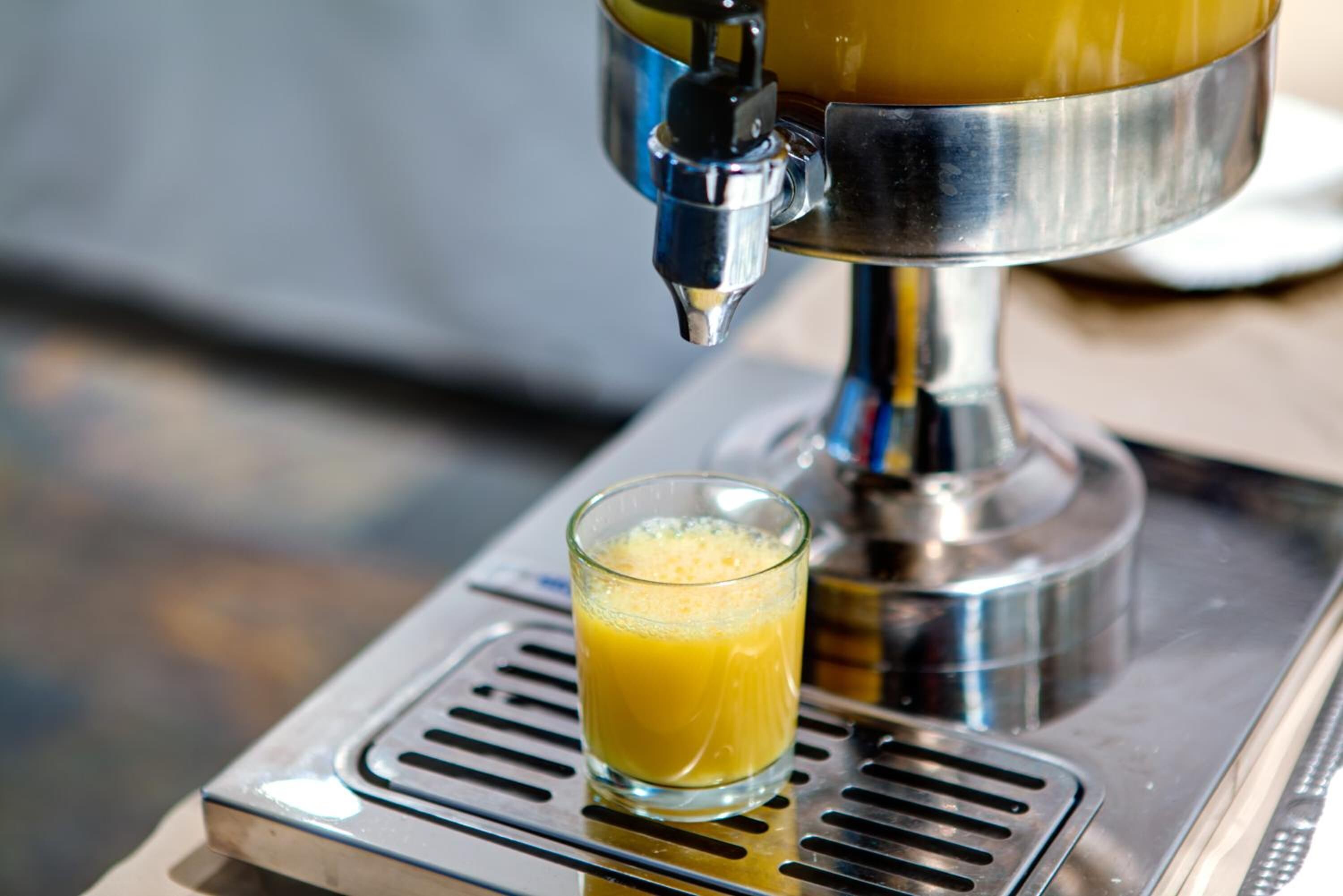 A coffee machine dispensing a glass of orange juice.