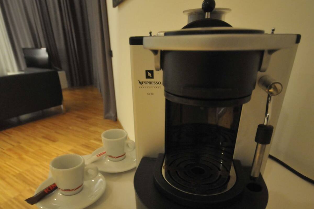 A Nespresso coffee machine on a table with two white cups and a spoon.