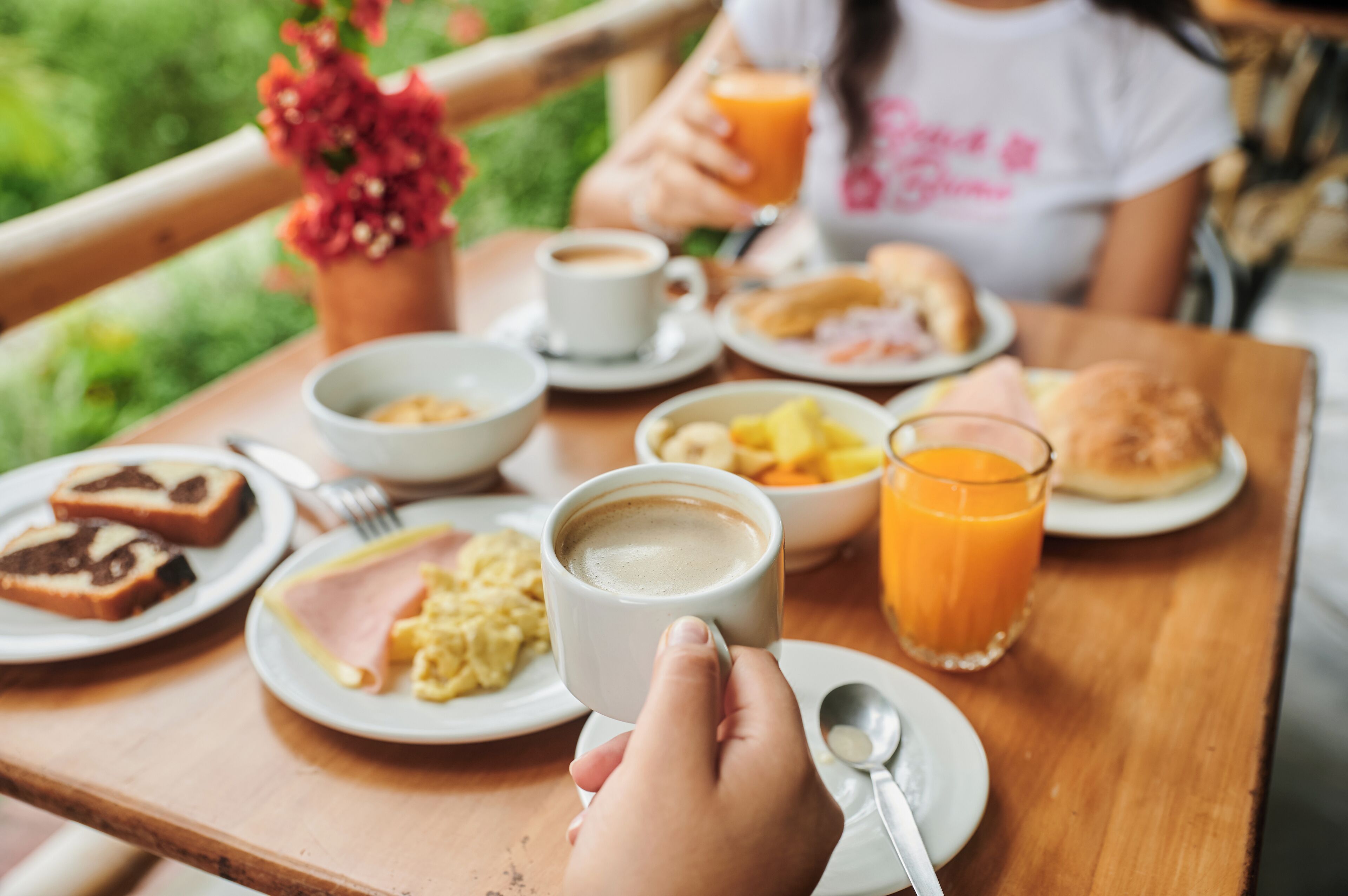A breakfast table with plates of food, a cup of coffee, and a glass of orange juice.