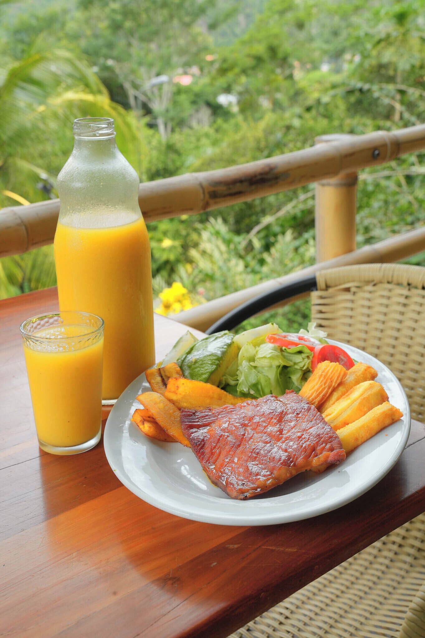 A table with a plate of food, a glass of juice, and a bottle of juice.