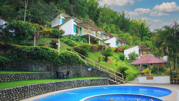 Una piscina con un muro de piedra y una escalera que conduce a una casa.