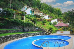 Una piscina con un muro de piedra y una escalera que conduce a una casa.
