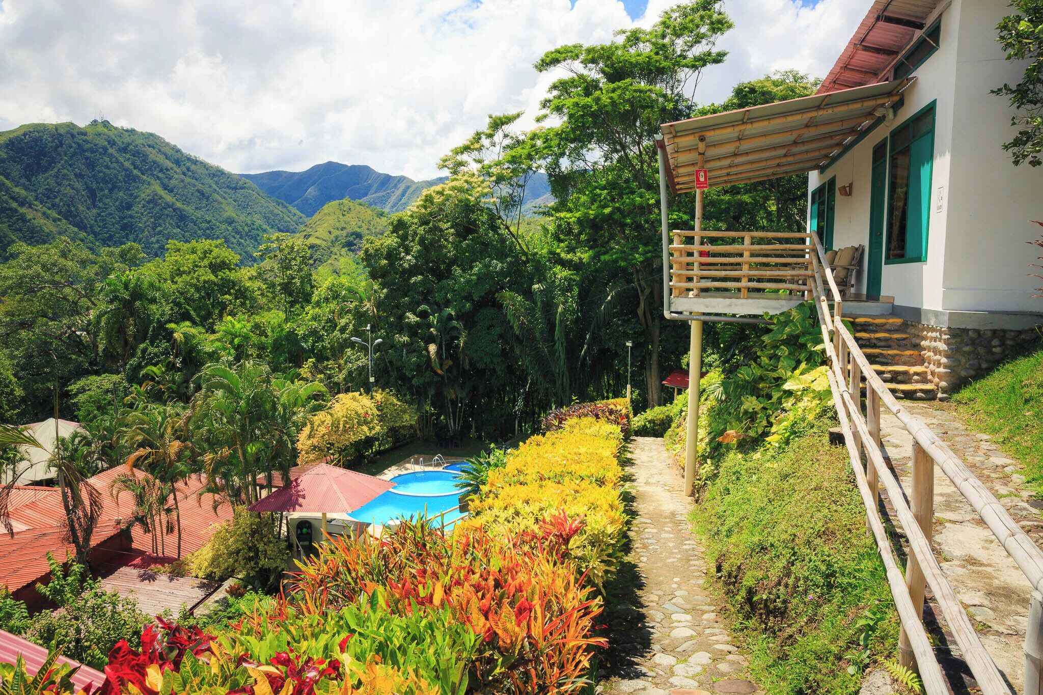Un hôtel doté d’une piscine, entouré d’une végétation luxuriante et de montagnes.