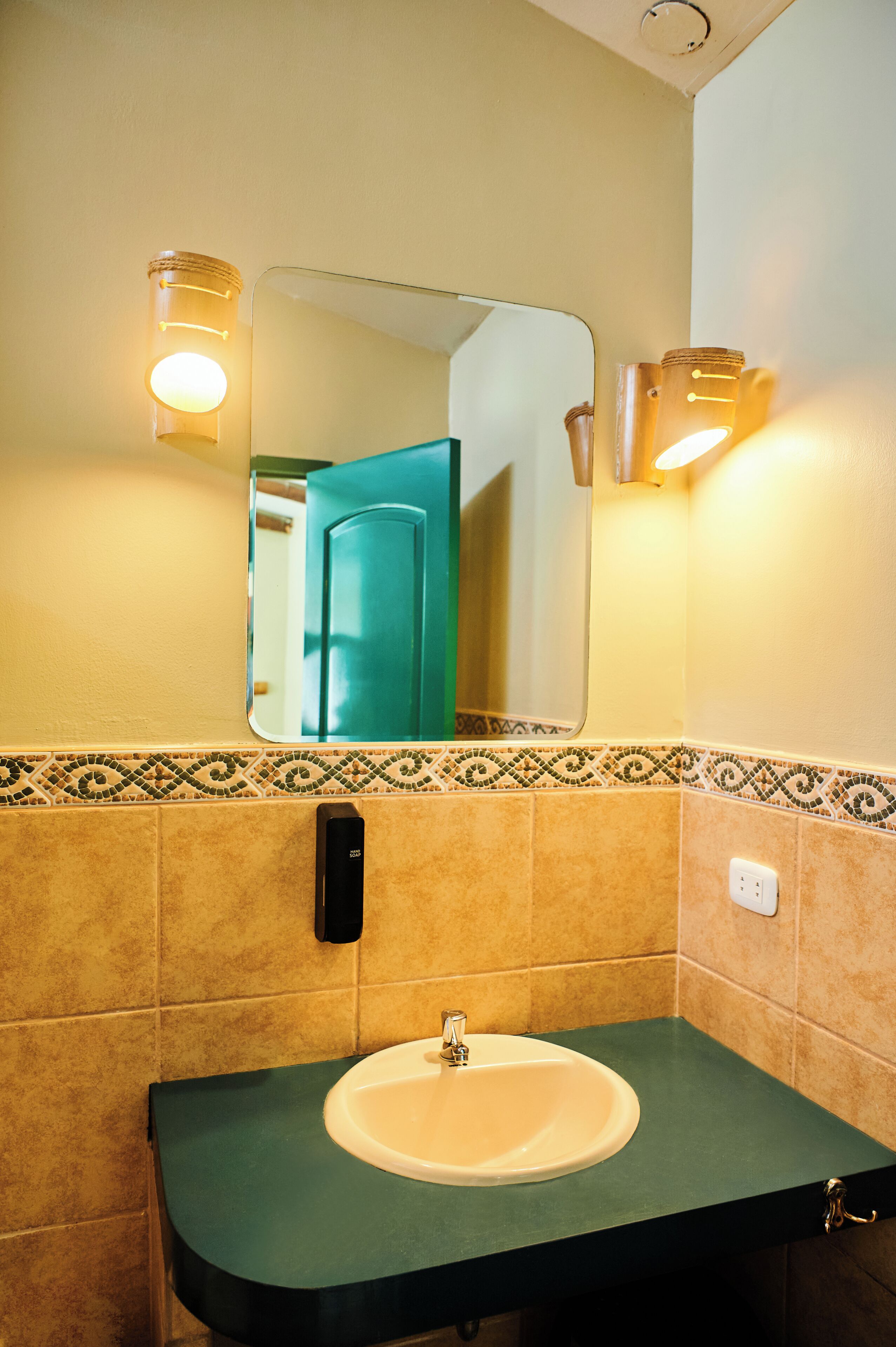 A bathroom with a green countertop, a white sink, a mirror, and two wall-mounted lights.