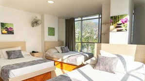 A hotel room with two beds, a large window, and artwork on the walls. - Hotel Alcaravan Medellín (Itagüí)