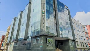 A modern hotel with a glass facade, multiple floors, and a prominent entrance. - Hotel Alcaravan Medellín (Itagüí)