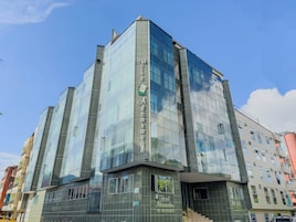 Un hotel moderno con fachada de vidrio, varios pisos y una entrada destacada.