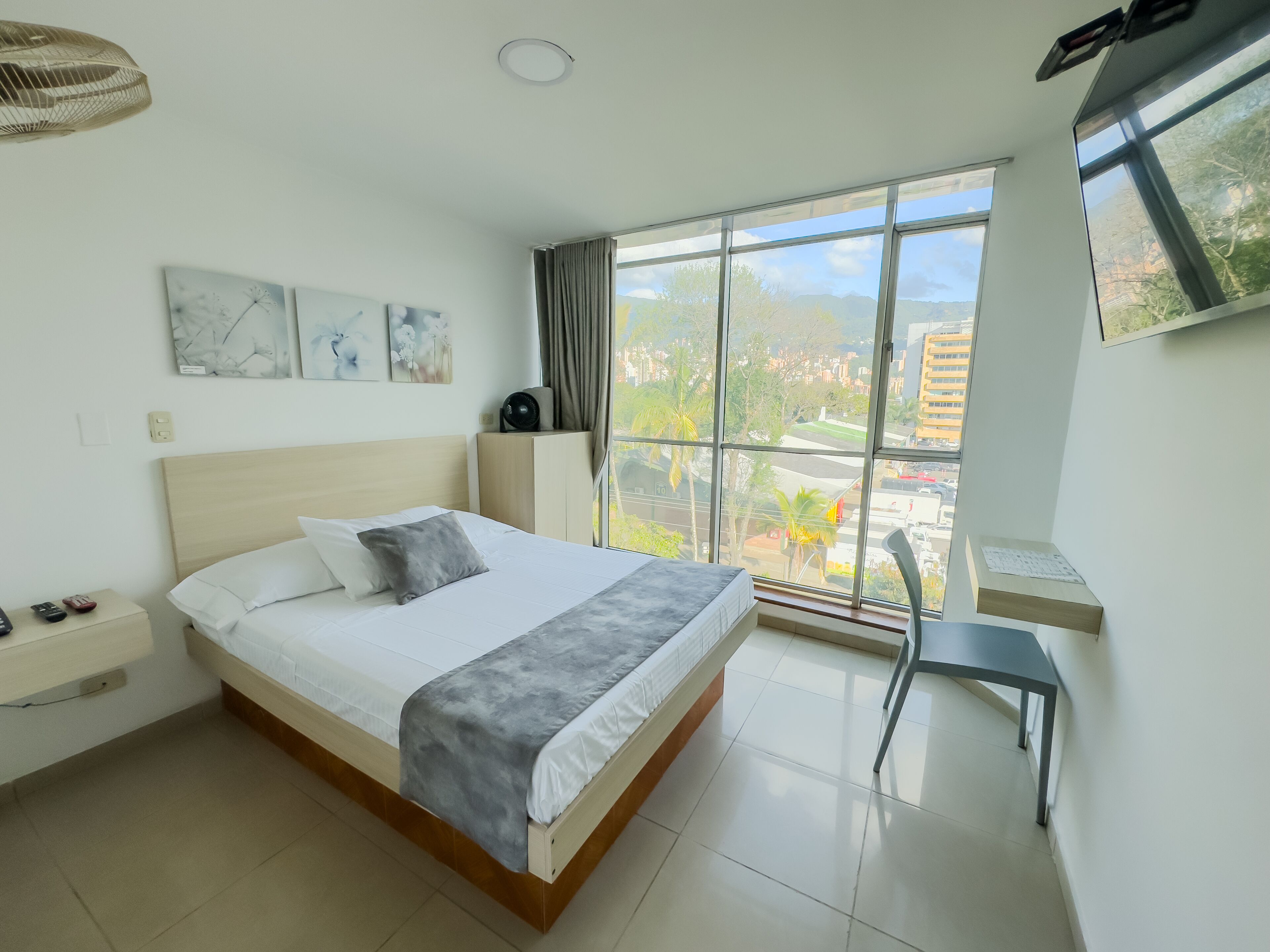 Una habitación de hotel moderna con una cama grande, un escritorio y vistas a la ciudad.