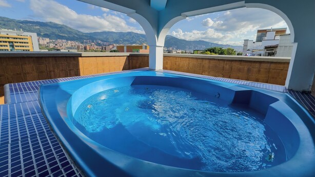 A rooftop swimming pool with a cityscape view. - Hotel Alcaravan Medellín (Itagüí)