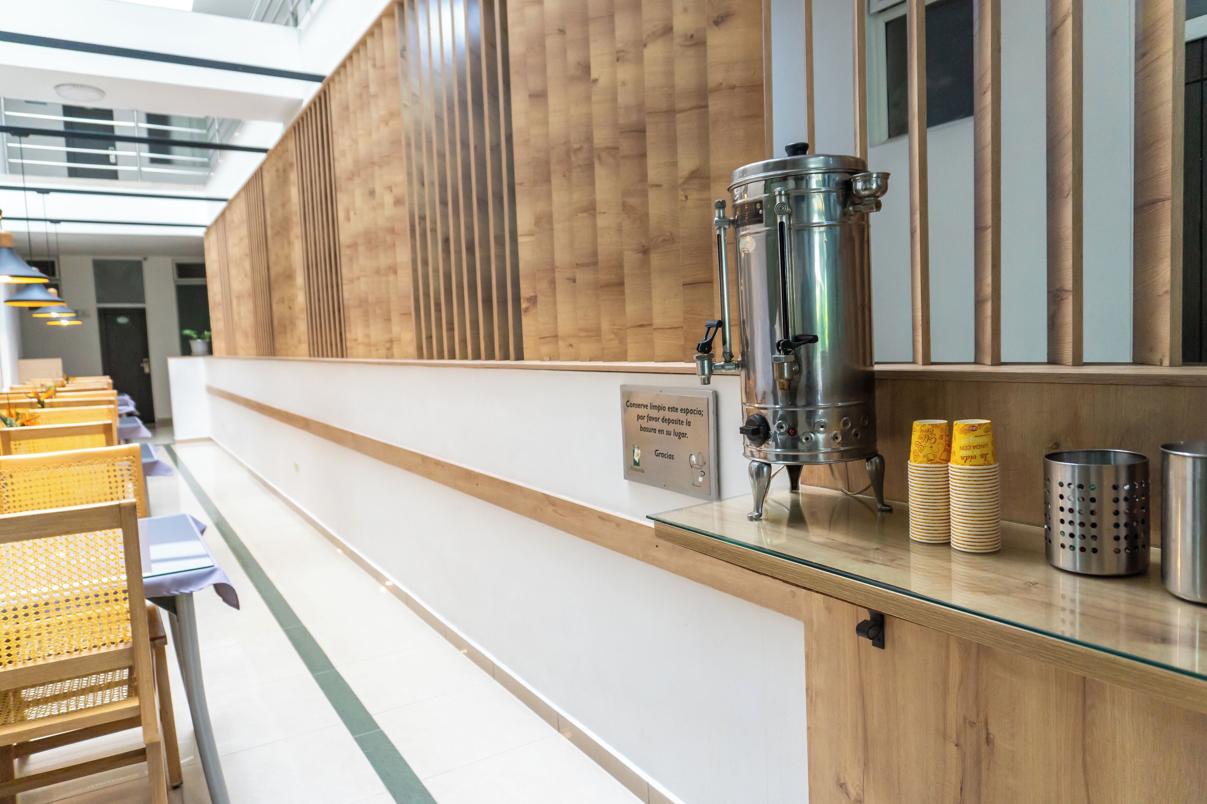A reception area with a coffee machine, stacked plates, and a sign indicating a deposit for parking.