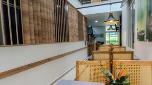 A modern interior with a long dining area, wooden partitions, and a central table with a vase of flowers. - Hotel Alcaravan Medellín (Itagüí)