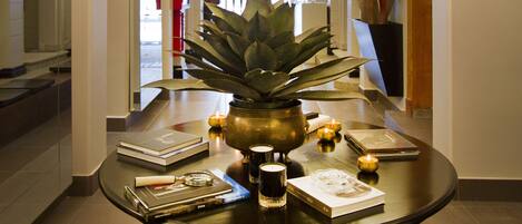 Una mesa redonda con una araña, una planta en maceta, algunos libros y velas.