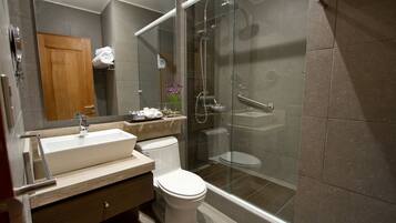 Un baño moderno con ducha de vidrio, lavamanos blanco y un inodoro.