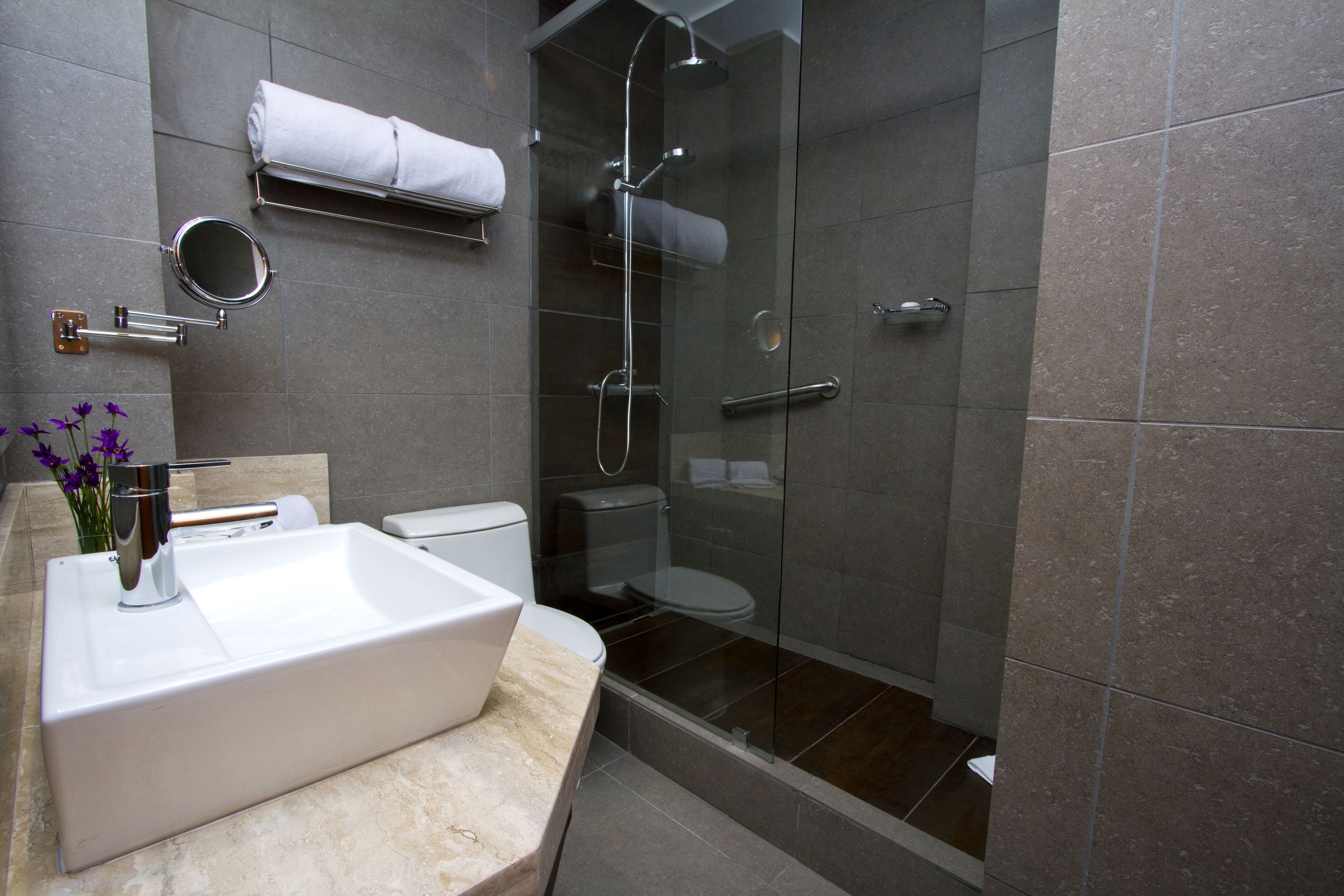 A modern bathroom with a large sink, toilet, and glass-enclosed shower.