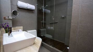 A modern bathroom with a large sink, toilet, and glass-enclosed shower.
