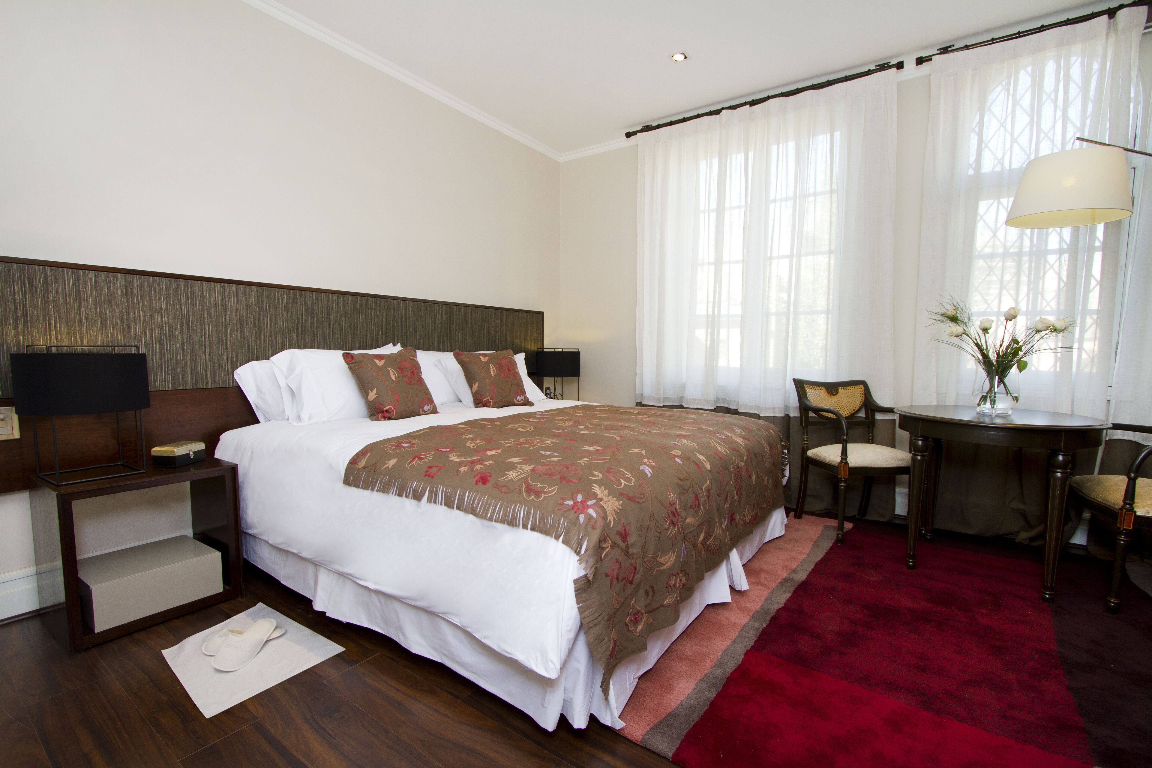 A hotel room with a large bed, a desk, and a chair.