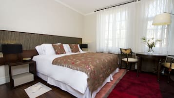A hotel room with a large bed, a desk, and a chair.