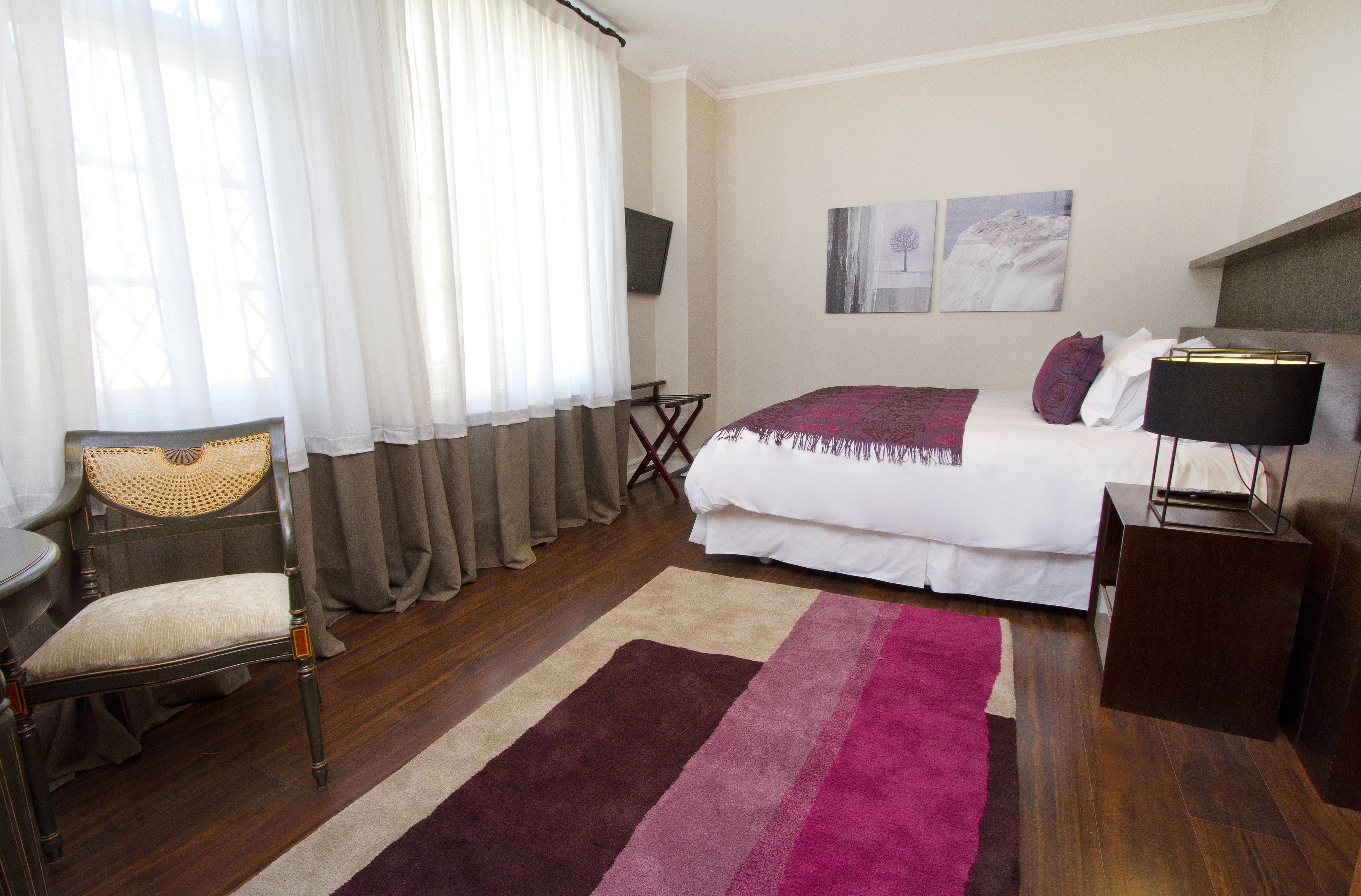 Un dormitorio con una cama, una silla, un escritorio y un televisor.