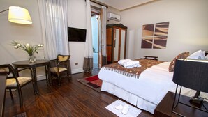 A hotel room with a bed, a desk, a chair, a TV, and a window with curtains. - Casa Bueras Boutique Hotel (Santiago)