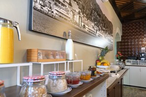 A breakfast bar with various food items and condiments, a large juice dispenser, and a framed picture on the wall. - Hotel Jardim Viana do Castelo (Viana do Castelo)