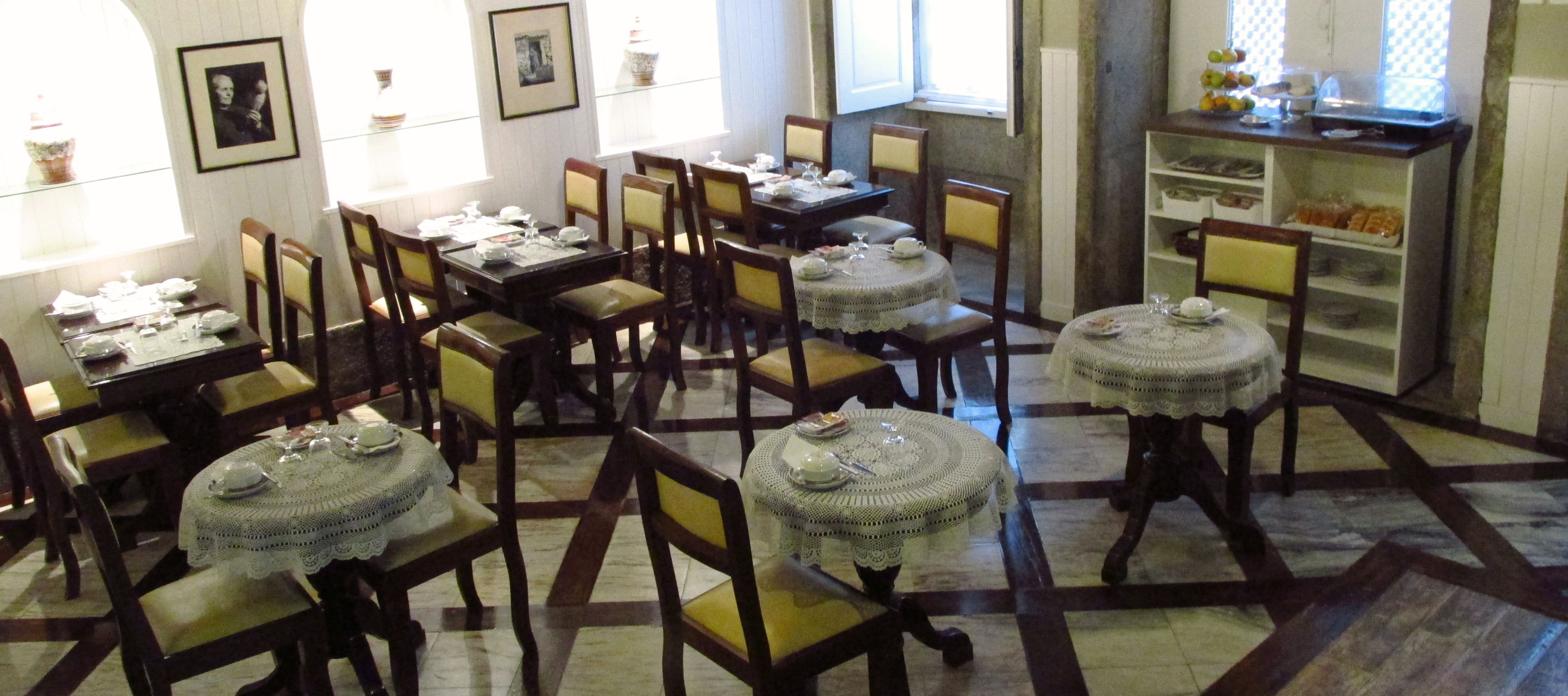 Comedor con varias mesas dispuestas para comer, sillas y una cocina al fondo.