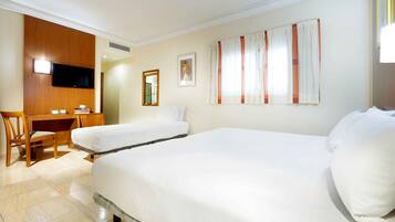 Habitación de hotel con dos camas, un escritorio, una silla, un televisor y una ventana con cortinas.